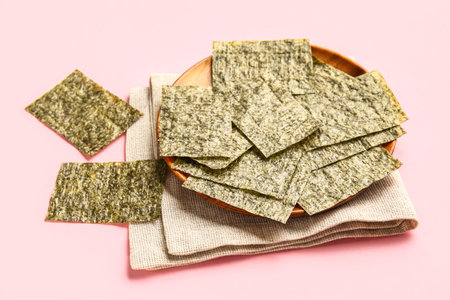 Plate with nori sheets on pink background