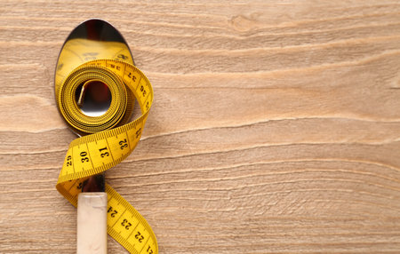Yellow measuring tape and spoon on wooden backgroundの写真素材