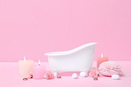 Small bathtub, burning candles, sponge, cotton balls and carnation flowers on color backgroundの写真素材
