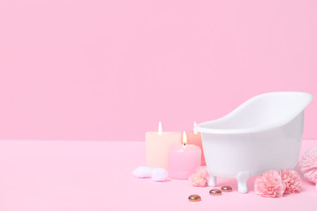 Small bathtub, burning candles and carnation flowers on color backgroundの写真素材