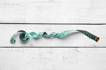 Blue measuring tape on white wooden background