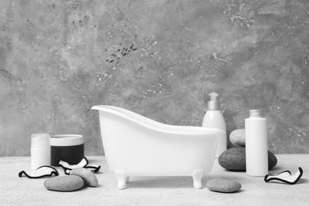 Small bathtub, spa stones, cosmetic products and cotton pads on tableの写真素材