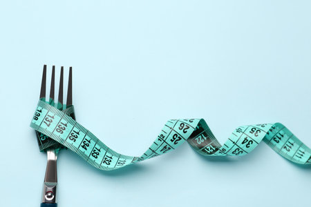 Measuring tape and fork on blue backgroundの写真素材