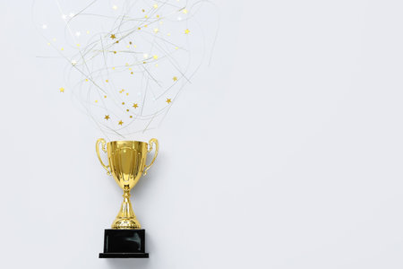 Gold cup with confetti on light backgroundの写真素材