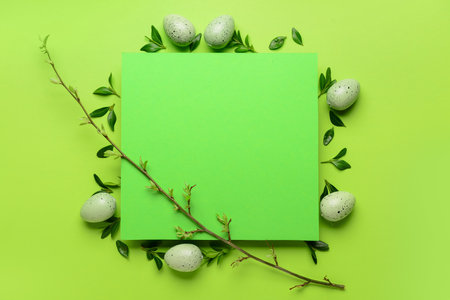 Blank card with Easter eggs, leaves and tree branch on green backgroundの写真素材