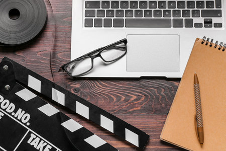 Notebook with laptop, film and movie clapper on dark wooden backgroundの写真素材