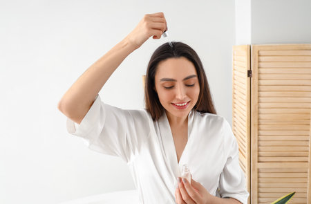 Woman with serum for hair loss treatment at homeの写真素材