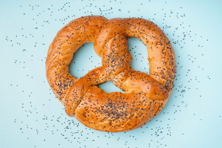 Tasty pretzel with poppy seeds on color backgroundの写真素材