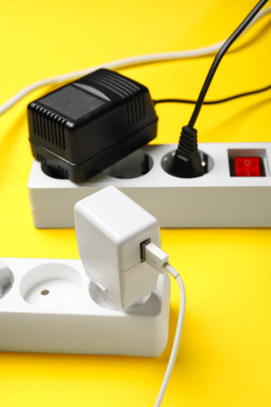 Electric extension cords with plugs on yellow background
