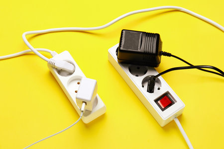Electric extension cords with plugs on yellow background