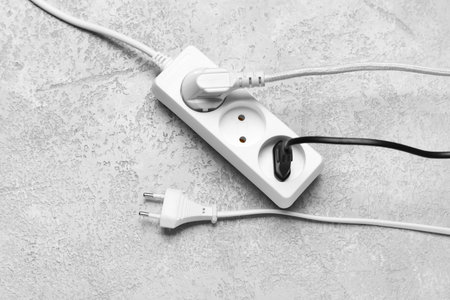 Electric extension cord with plugs on gray grunge background