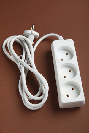 Electric extension cord on brown background