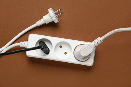 Electric extension cord with plugs on brown background