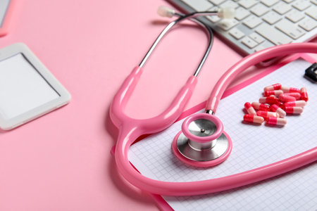 Stethoscope, pc keyboard, pills and clipboard on pink background, closeupの写真素材