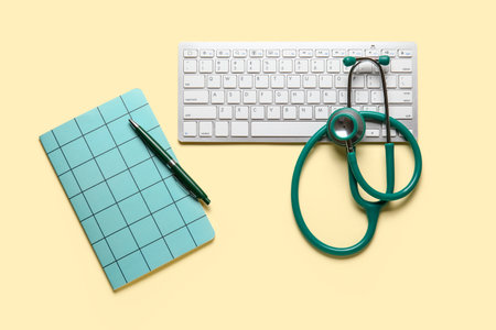 Stethoscope, notebook and pc keyboard on yellow backgroundの写真素材