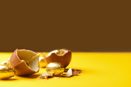 Chocolate Easter eggs on yellow table against brown backgroundの写真素材