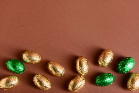 Chocolate Easter eggs in foil on brown backgroundの写真素材