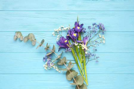 Beautiful flowers with eucalyptus branch on blue wooden background