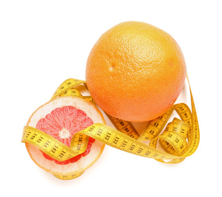 Cut and whole grapefruit with yellow measuring tape on white background. Diet conceptの写真素材