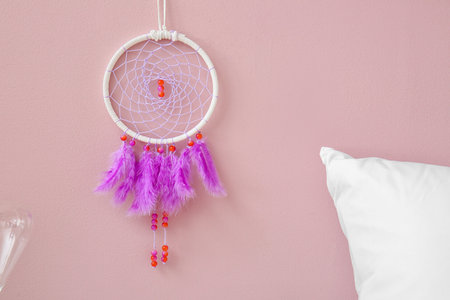 dream catcher hanging on pink wall in bedroomの写真素材