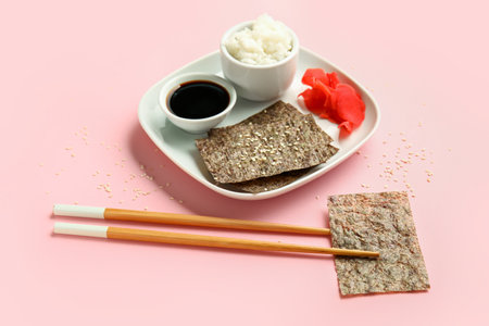 Plate with nori sheets, rice, ginger and soy sauce on color backgroundの写真素材