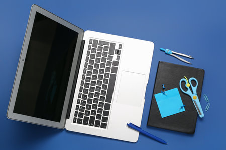 Composition with laptop, stationery and notebook on blue backgroundの写真素材