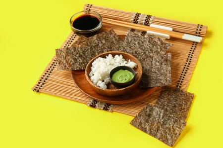 Plate with nori sheets, rice, wasabi and soy sauce on yellow backgroundの写真素材