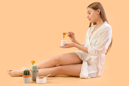 Young woman with sugaring paste and cacti on beige backgroundの写真素材