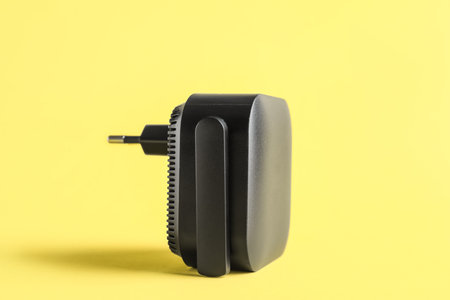 Black WiFi repeater on yellow background