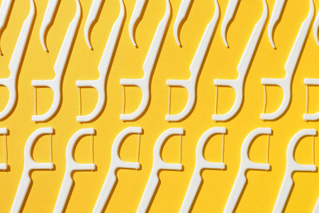 Many floss toothpicks on yellow background