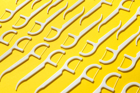 Many floss toothpicks on yellow background