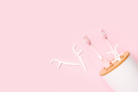 Overturned toothbrush holder and floss toothpicks on pink backgroundの写真素材