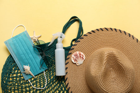 Composition with bottle of sunscreen cream, medical mask and beach accessories on yellow background. melanoma conceptの写真素材