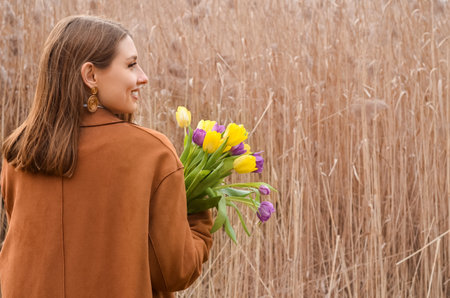 Young woman with tulips near pampas grass outdoors, back viewの写真素材