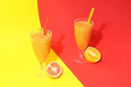 Glasses of healthy orange and grapefruit smoothie on colorful background