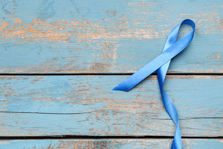 Blue awareness ribbon on color wooden background. Prostate cancer conceptの写真素材