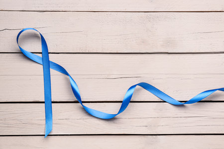 Blue satin ribbon on light wooden background. Prostate cancer conceptの写真素材