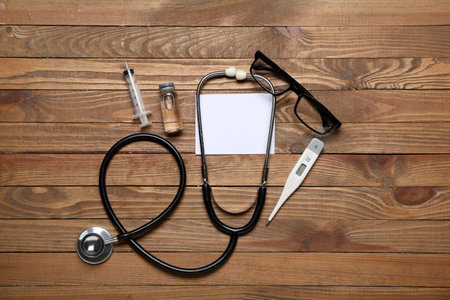 Composition with blank card, stethoscope, thermometer, eyeglasses and medicines on wooden background. melanoma conceptの写真素材