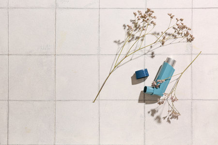 Asthma inhaler with flowers on white tile backgroundの写真素材