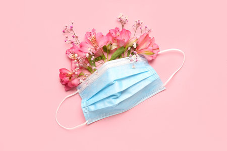 Medical mask with flowers on pink background. Asthma conceptの写真素材