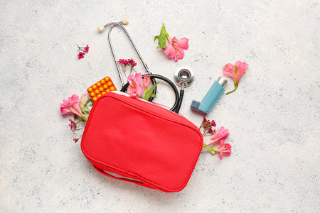 First aid kit with asthma inhaler, pills, stethoscope and flowers on grunge backgroundの写真素材