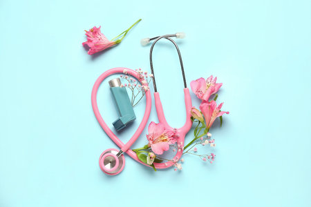 Asthma inhaler with stethoscope and flowers on blue backgroundの写真素材