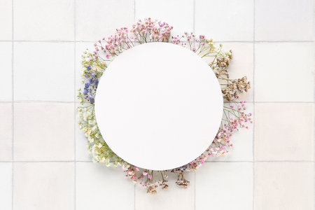 Blank card with gypsophila flowers on white tile backgroundの写真素材