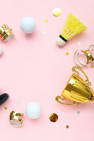 Frame made of gold cup with sports equipment on pink backgroundの写真素材
