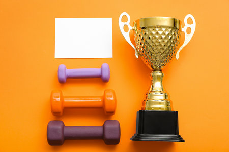 Blank card with gold cup and dumbbells on red backgroundの写真素材