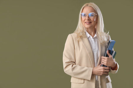 Mature teacher with notebooks on green backgroundの写真素材