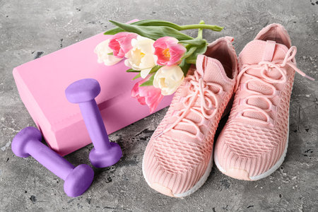 Sneakers with tulips, block and dumbbells on dark backgroundの写真素材