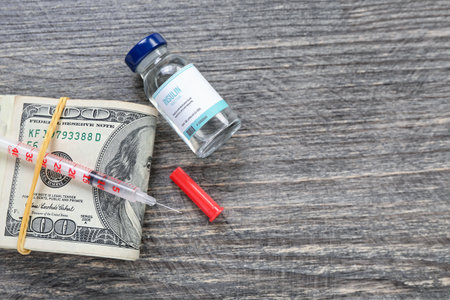 Insulin with syringe and money on dark wooden background. Expensive medicine conceptの写真素材