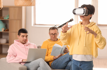 Little boy with his dad and grandfather using VR glasses at homeの写真素材