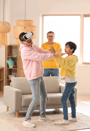Young man with his little son and father using VR glasses at homeの写真素材